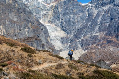 Uzun yürüyüşe çıkan kimse büyük portakal sırt çantası ile 