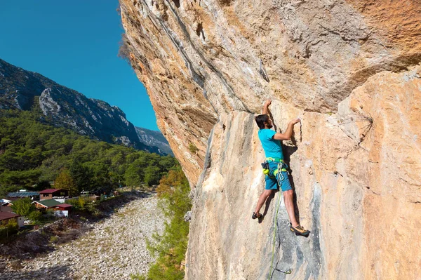 オレンジ色の岩の上にぶら下がっている登山家 — ストック写真