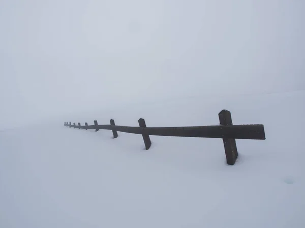 Clôture en bois submergée par la neige et enveloppée dans la brume — Photo