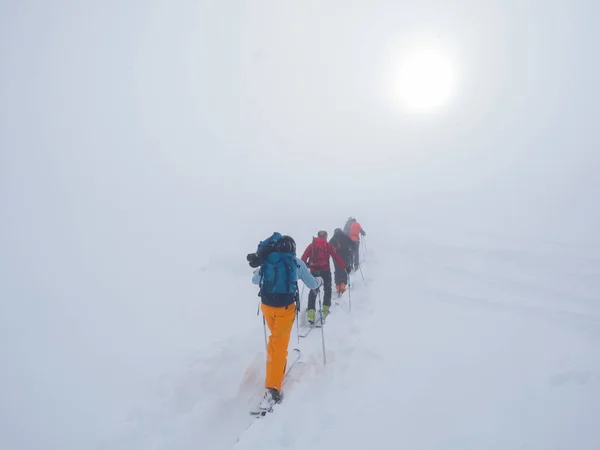 Sci alpinismo: gruppo di persone in viaggio verso la vetta in una giornata di nebbia e nebbia — Foto Stock