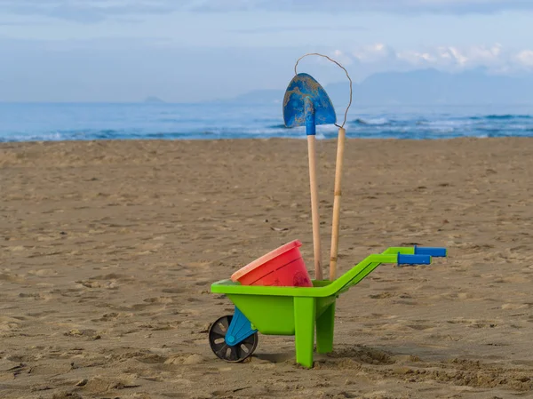 Toys on the beach plastic wheelbarrow, bucket and spade — Stock Photo, Image