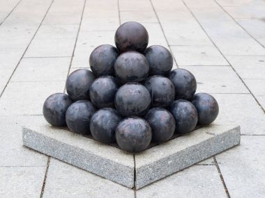 old black  iron cannon balls arranged in pyramid shape clipart