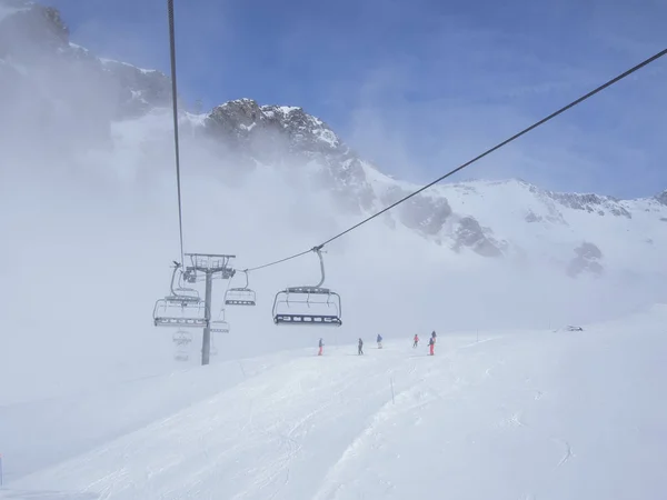 Chair lifts, skiers, and mountain peaks emerge from the fog