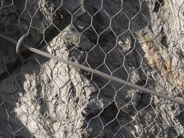 Metallgitter und Drähte schützen Straßen vor Erdrutschen und Steinschlag lizenzfreie Stockfotos