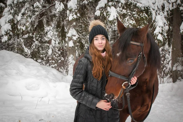 Young girl and horse in a winter forest
