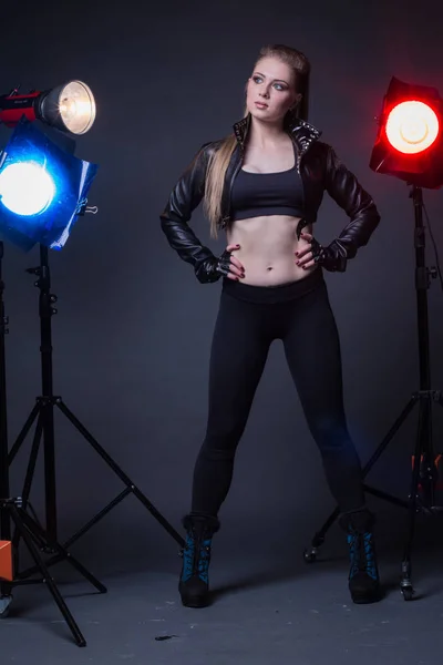 Girl in a leather jacket on stage and colored spotlights