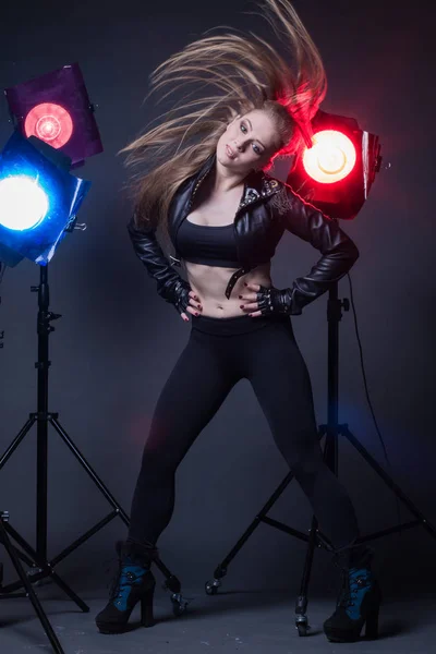 Girl in a leather jacket on stage and colored spotlights