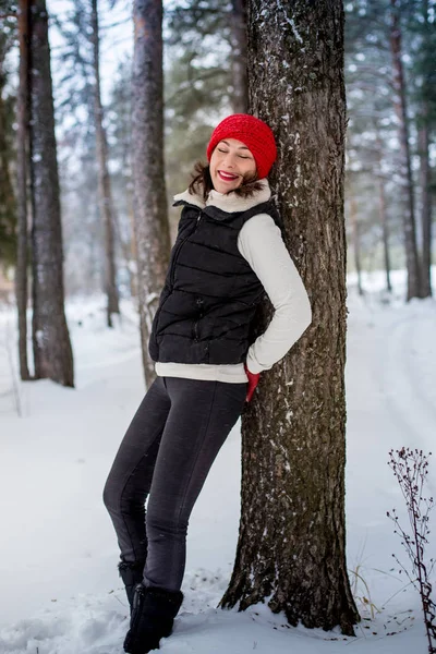 Girl in a red cap and warm jacket in the forest in a winter