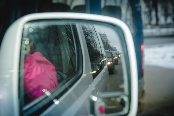 Reflection of traffic flow in left side rear view mirror in the city