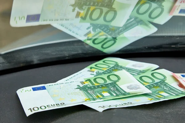 Euro banknotes on the dashboard and their reflection in the windshield inside of a car