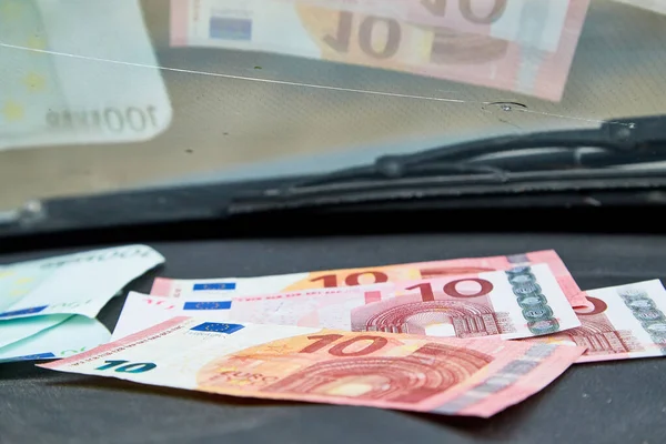 Euro banknotes on the dashboard and their reflection in the windshield inside of a car