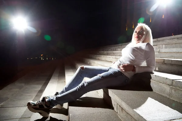 Ugly woman on the steps of stair in the city at night with light