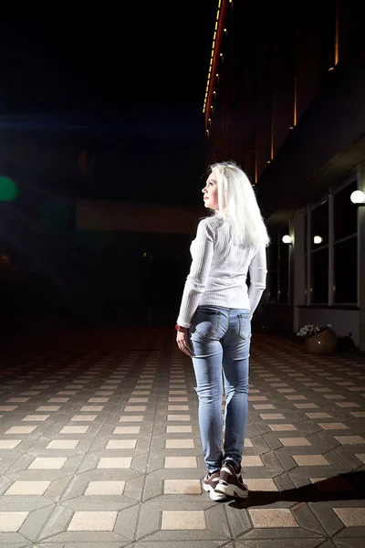 woman in the city at night with lighting flashes in the bla