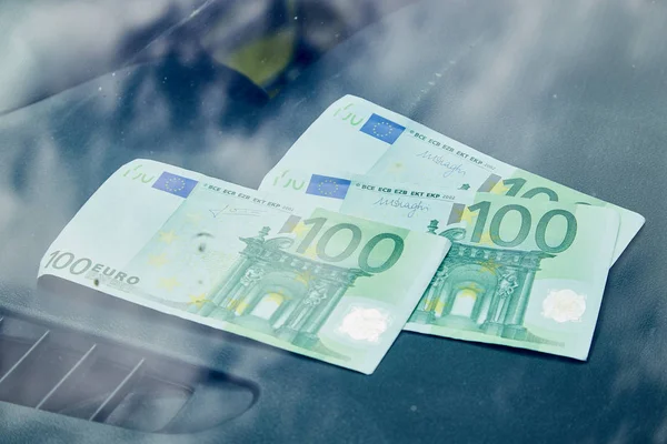 Euro banknotes on the dashboard and their reflection in the windshield inside of a car