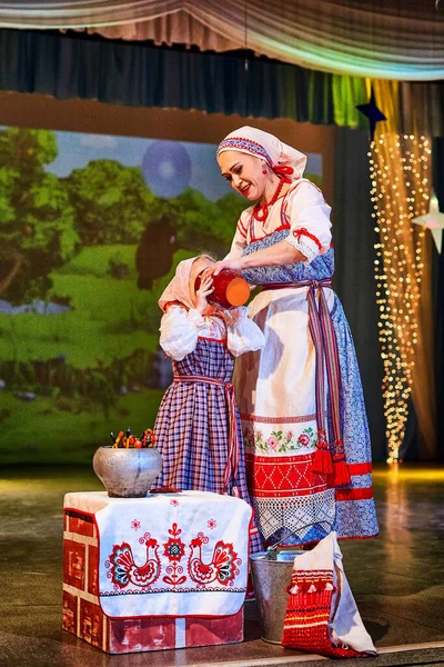 Little girl and adult woman in Russian national dress rehearsing on stage. Mother and daughter sing and dance together