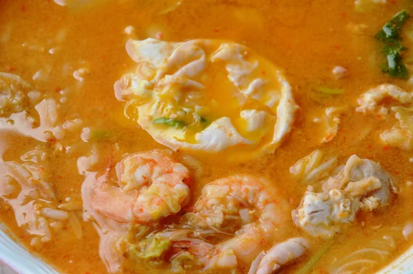 Nasi rebus topping krim telur kuning dan makanan laut dalam sup pedas di atas mangkuk — Stok Foto