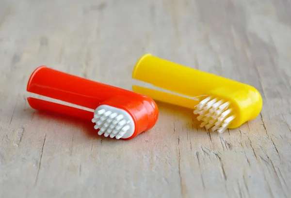 Κατοικίδιο ζώο οδοντόβουρτσα χρησιμοποιείται από τεθεί σε δάχτυλο σε ξύλινη σανίδα — Φωτογραφία Αρχείου