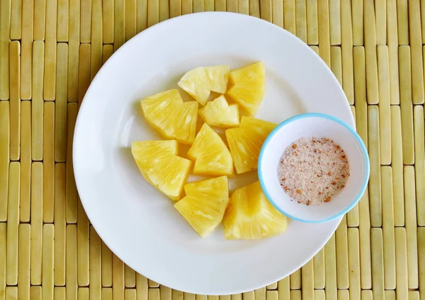 Скибочка ананаса, що занурюється зі змішаною цукровою сіллю та перцем на білій тарілці — стокове фото
