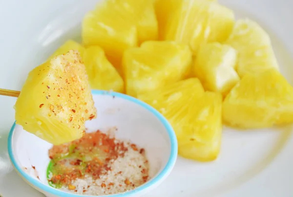 Скибочка ананаса, що занурюється зі змішаним цукром сіль і перець на дерев'яній паличці — стокове фото