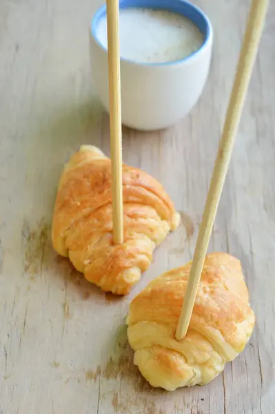 Croissant stab chopstick séta a forró csésze kávé — Stock Fotó