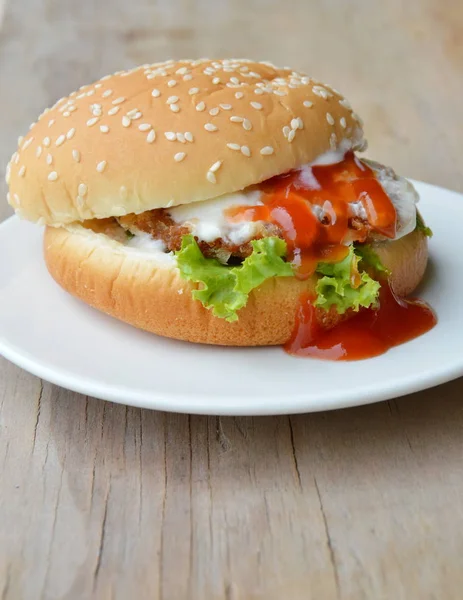 Varkensvlees hamburger dressing tomatensaus en mayonaise op schotel — Stockfoto