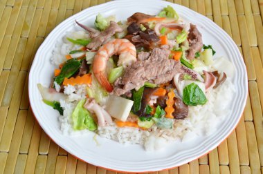 Deniz ürünleri ve domuz kızarmış karışık sebze üzerinde pirinç ilave edin.