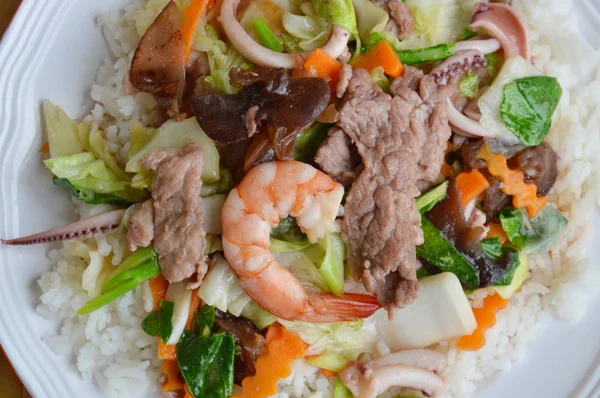 Deniz ürünleri ve domuz kızarmış karışık sebze üzerinde pirinç ilave edin.