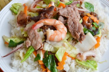 Deniz ürünleri ve domuz kızarmış karışık sebze üzerinde pirinç ilave edin.