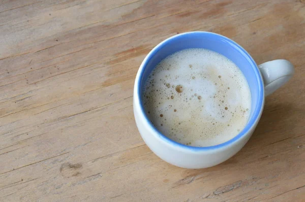 Кофе с молочной пеной на деревянном столе — стоковое фото