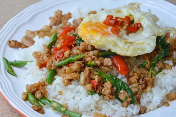 Babi goreng aduk pedas dengan daun kemangi topping telur di atas nasi — Stok Foto