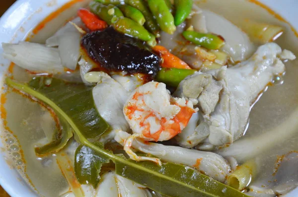 Gekookte schaal-en schelpdieren met been pittige kippensoep topping van gebakken chili plakken op bowl — Stockfoto