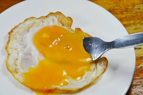 Oeuf frit avec jaune crémeux pendant que la fourchette poignarde — Photo