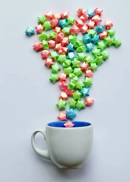Papel estrela colorido flutuando a partir de xícara de café no fundo branco — Fotografia de Stock