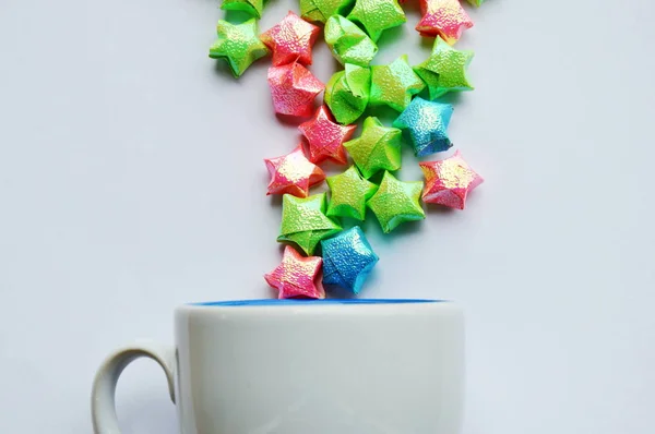 Papel estrela colorido espirrando de xícara de café no fundo branco — Fotografia de Stock