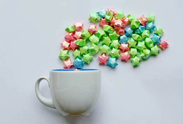 Papel estrela colorido flutuando a partir de xícara de café no fundo branco — Fotografia de Stock