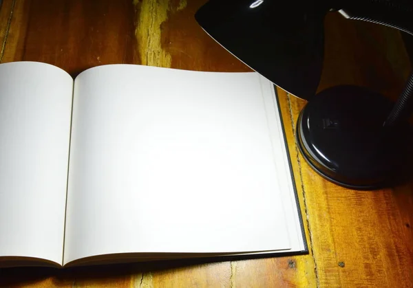Bílá kniha knihy a čtení lampa na dřevěný stůl v noci — Stock fotografie