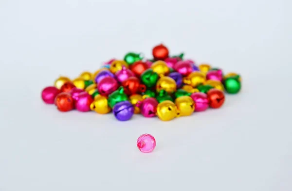 Pink plastic bead and colorful bell on white background — Stock Photo, Image
