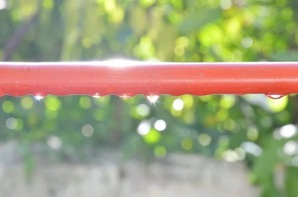 Gota de agua en la línea de ropa de aluminio rojo reflejo de la luz solar — Foto de Stock