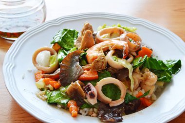 Deniz ürünleri ve domuz kızarmış karışık sebze üzerinde pirinç ilave edin.