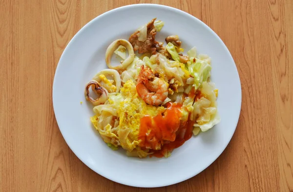 Gebratene Reisnudeln mit Meeresfrüchten und Kohl-Dressing-Chilisoße auf Teller rühren — Stockfoto