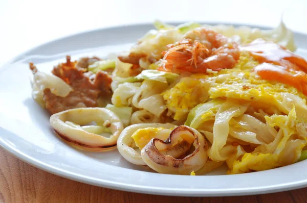 Gebratene Reisnudeln mit Meeresfrüchten und Kohl-Dressing-Chilisoße auf Teller rühren — Stockfoto