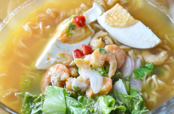 Fideos instantáneos hervidos picantes rematando huevo salado y camarones secos en un tazón —  Fotos de Stock