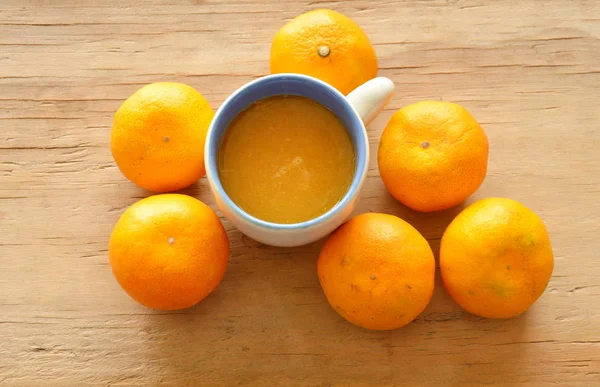 Presser l'orange dans la tasse et la mandarine sur la planche de bois — Photo