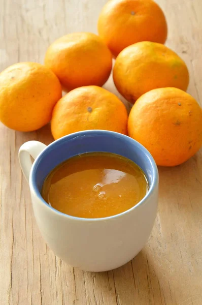 ส้มบีบในถ้วยและแมนเดอรีนบนกระดานไม้ — ภาพถ่ายสต็อก