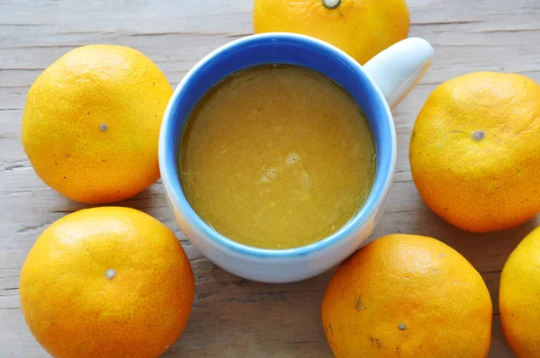 Jus d'orange en tasse et mandarine sur table en bois — Photo