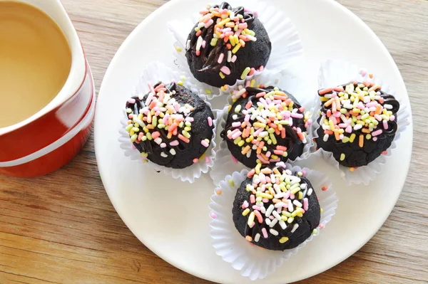 Bola de chocolate coronando caramelos de colores y taza de café rojo — Foto de Stock