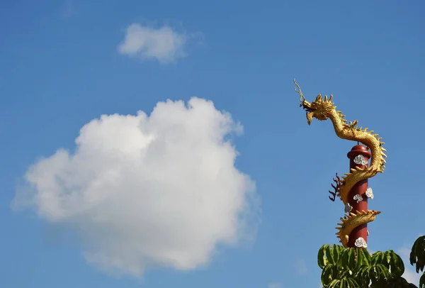 Estatua de dragón chino dorado rodar sobre poste y gran fondo de nube — Foto de Stock