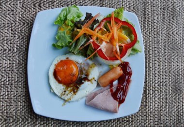 sahanda yumurta kare plaka üzerinde Soya soslu domuz sosisi ve salata giyinme