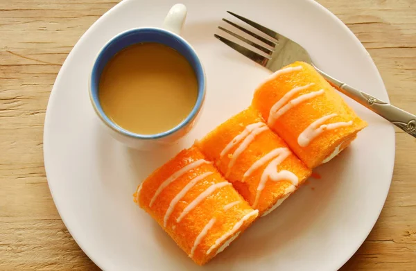 Pastel de naranja rollo relleno de crema y café en el plato — Foto de Stock