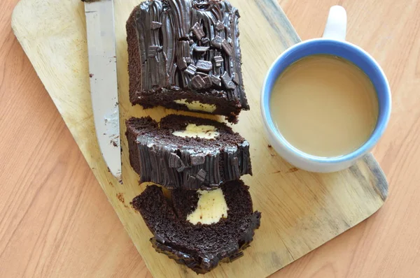 Mörk chokladkaka rulle fylld kräm äter par med kaffe på trä chop block — Stockfoto